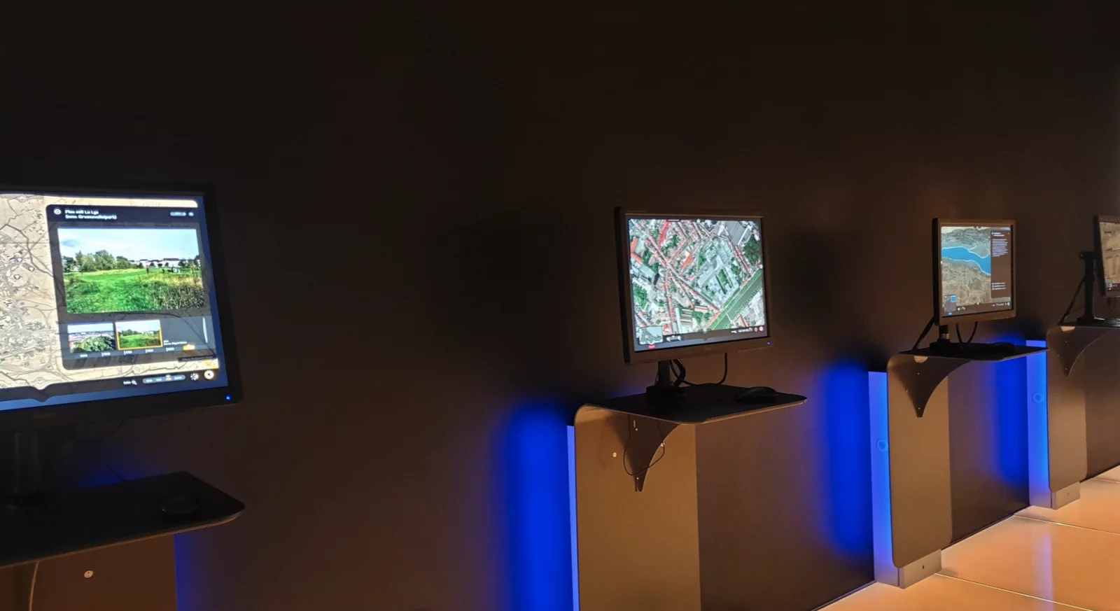 Interactive screens at STAM showing historical maps and aerial photos of Ghent