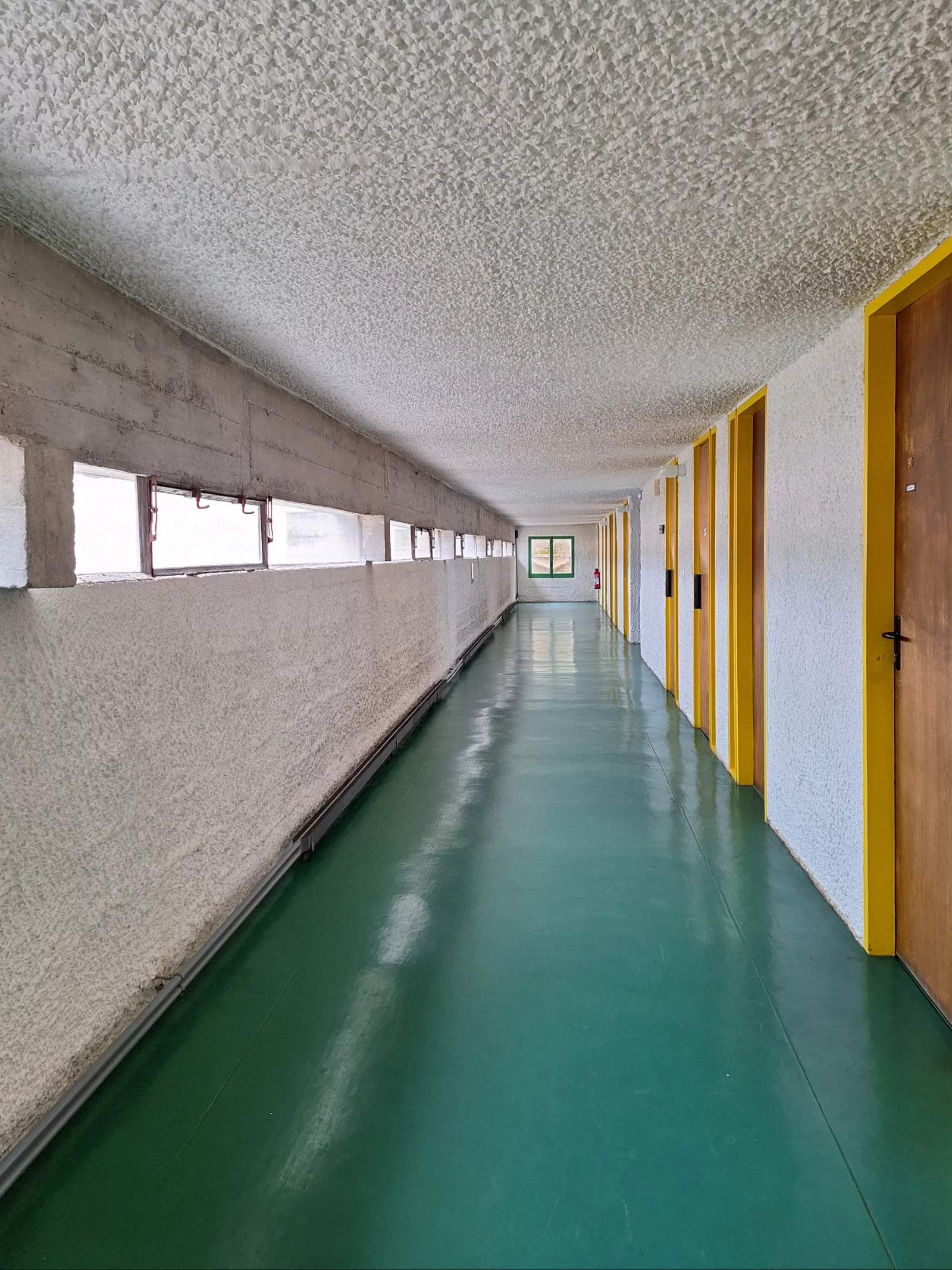 The corridor with the cell doors, green floor and yellow frames