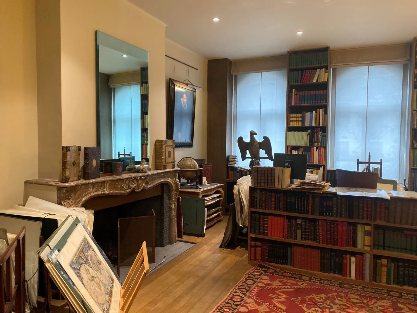 Het interieur van Antiquariaat Sanderus: boekenkasten tot aan het plafond, een schouw met een globe, een houten adelaar en ingelijste oude kaarten tegen de muur