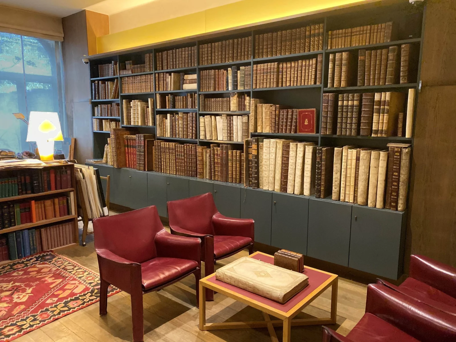 The Sanderus antiquarian bookshop in Ghent: a wall of old leather-bound books, two burgundy armchairs and a vellum folio on the coffee table