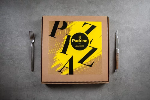 Een gele pizzadoos van Il Padrino met grote zwarte letters, tussen een vork en een mes