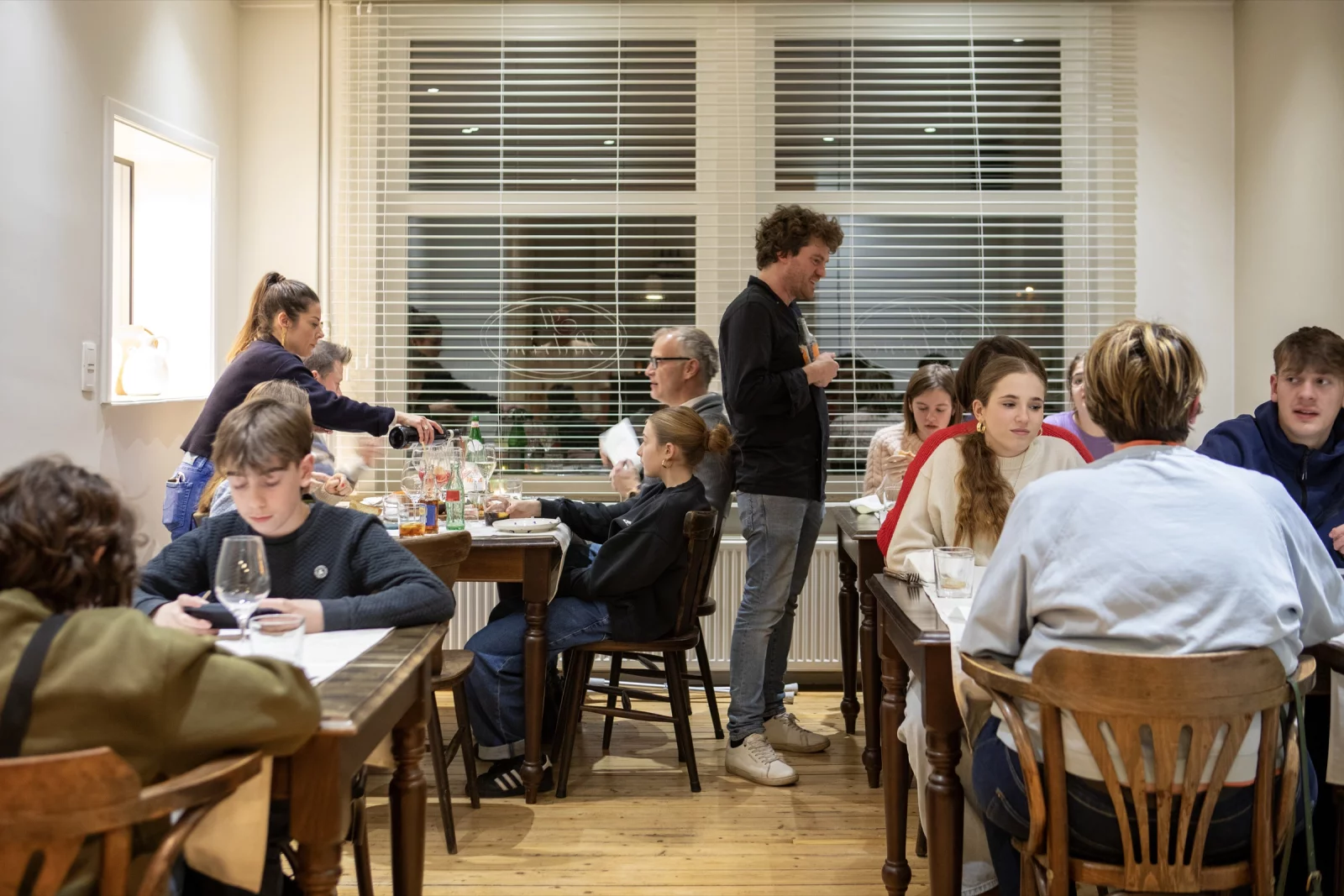 Een volle zaal bij Il Padrino, met gasten aan tafel en bediening tussen de tafels