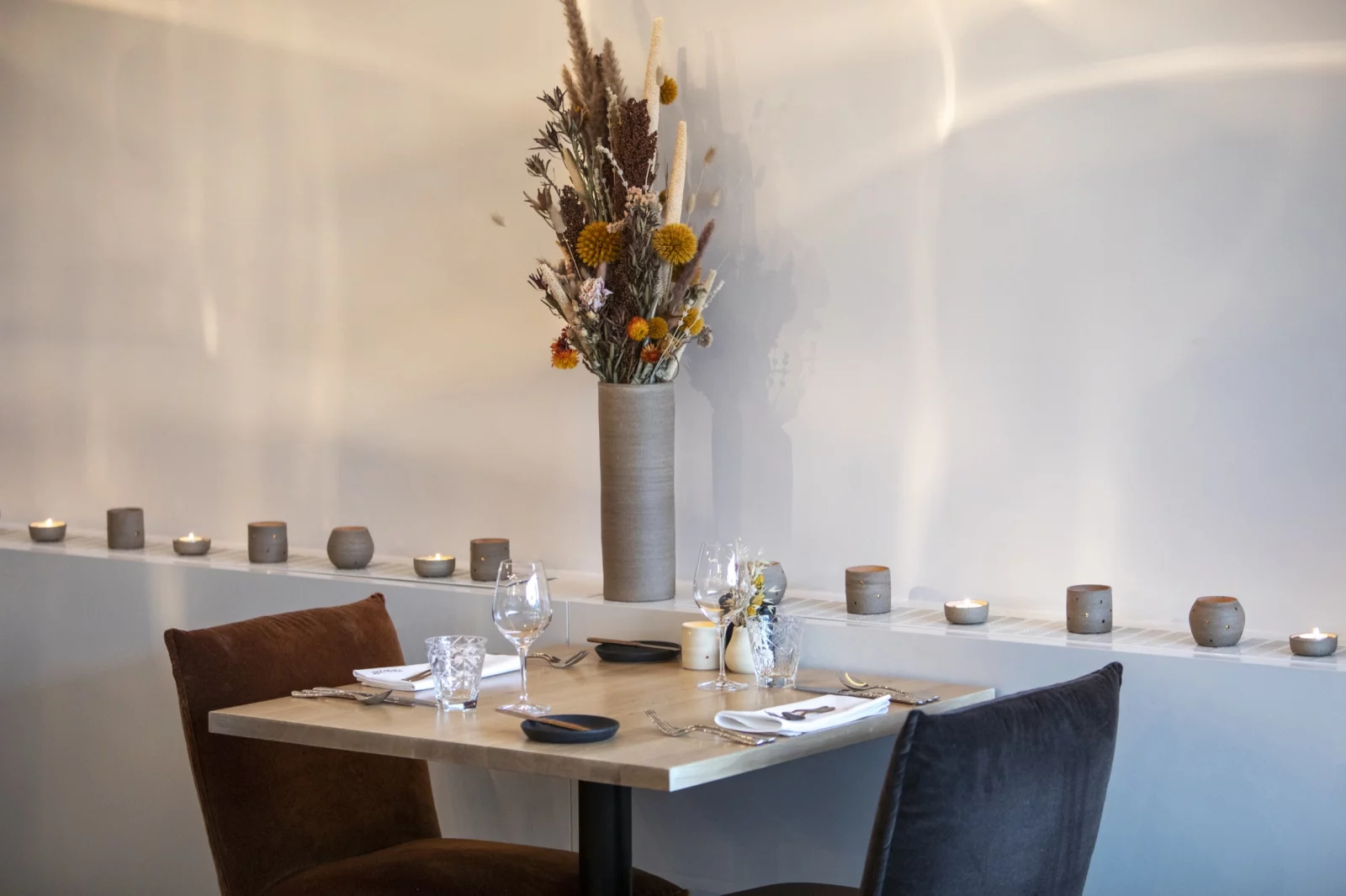 Een gedekte tafel in de zaal van Fou du Go&ucirc;t, met kaarsjes en droogbloemen