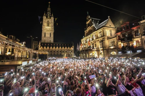 Een zee van gsm-lichtjes voor het podium op het Sint-Baafsplein, met het Belfort op de achtergrond