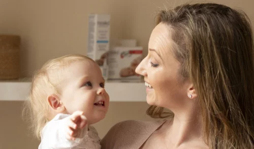 Moeder en baby die elkaar lachend aankijken